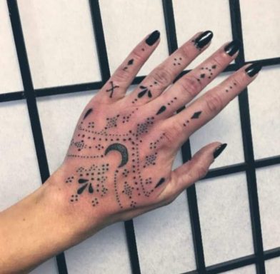 A hand adorned with intricate black henna designs and painted nails.