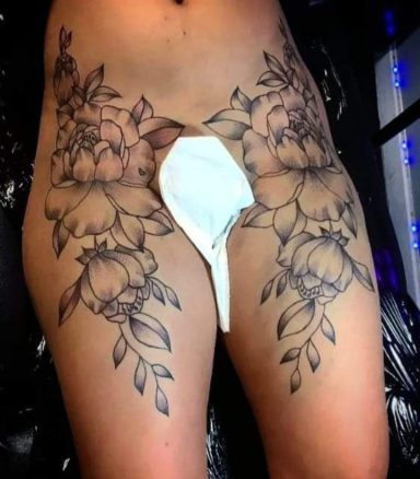 Tattoo design featuring flowers and leaves on the thighs, with a white garment in the centre.