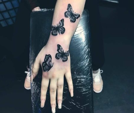 Black butterfly tattoos on the hand and wrist.
