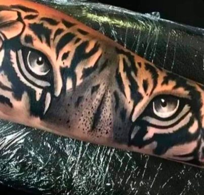 Realistic tiger eyes tattoo on an arm, detailed and expressive.