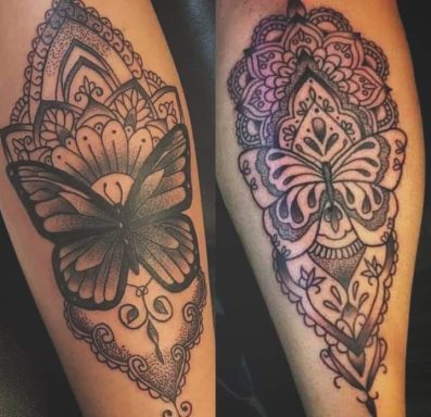 Black butterfly tattoos with ornate patterns on forearms.