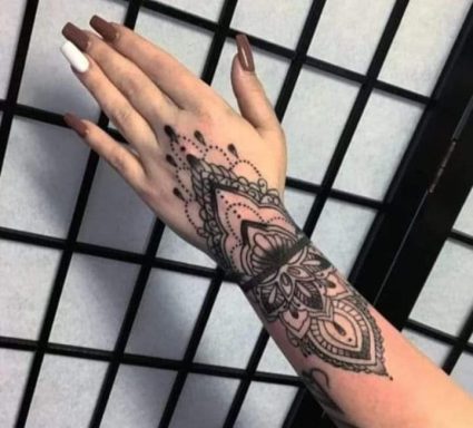 A hand with intricate henna tattoo against a decorative background.