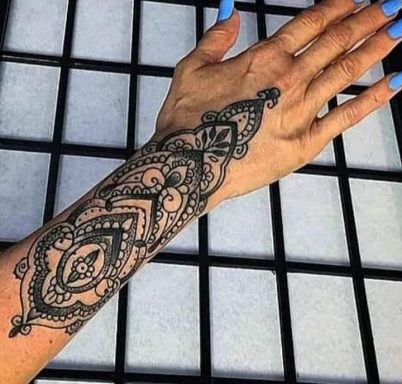 A detailed black tattoo design on a person's forearm surrounded by a grid background.