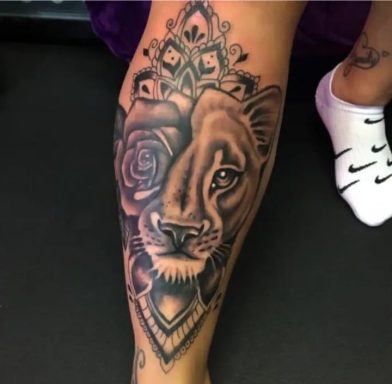 Tattoo of a lion's face combined with a rose, surrounded by ornate detailing.