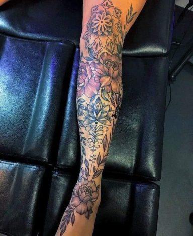 A detailed black and grey floral tattoo covering a leg.