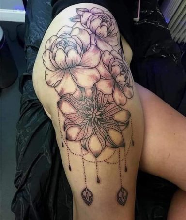 Tattoo featuring large flowers and geometric shapes on a thigh.