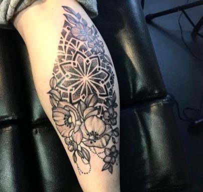 Detailed floral and geometric tattoo design on a calf.