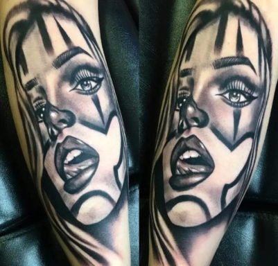 Black and grey tattoo of a woman's face with abstract features and geometric lines.