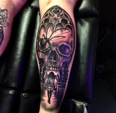 Detailed black and grey tattoo of a skull with a spider and intricate designs.