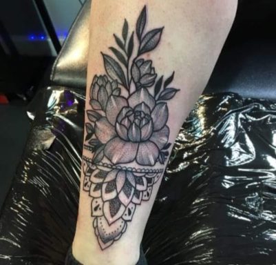 Black and grey floral tattoo on the calf featuring peonies and a mandala design.