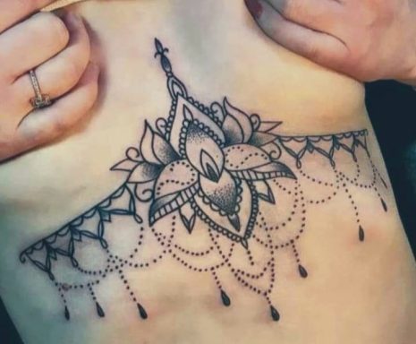 Ornate black ink tattoo of a lotus flower with intricate details and dangling patterns.