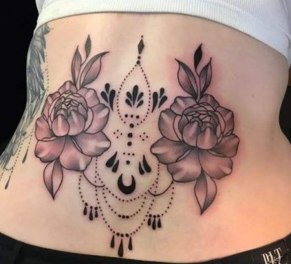 Floral tattoo featuring two roses and decorative elements on a lower back.