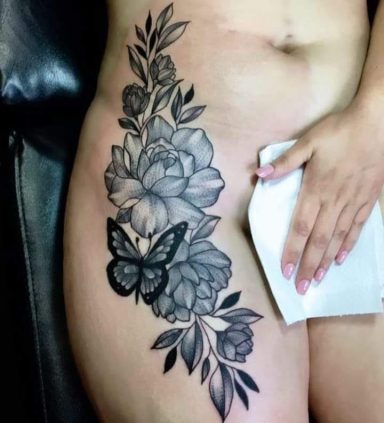 Black and grey flower tattoo with a butterfly on the thigh.