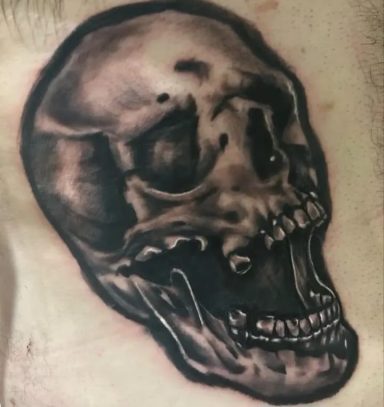 Realistic black and grey tattoo of a skull on skin.