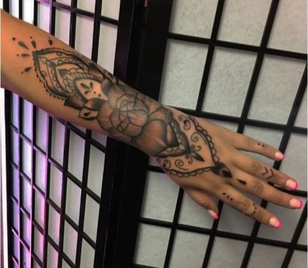 A detailed black ink tattoo of a goddess on a person's forearm with intricate designs.