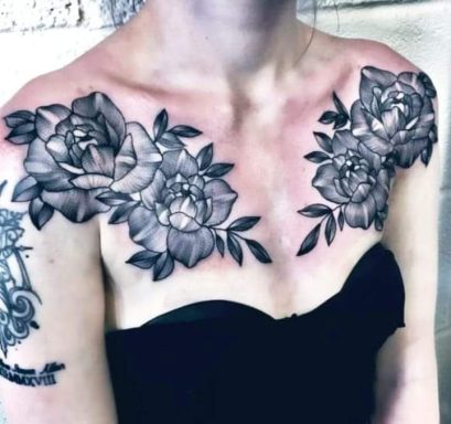 Black and grey floral tattoos on the shoulders and upper chest of a person.