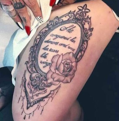 Tattoo featuring a rose and ornate frame with a quote inside.